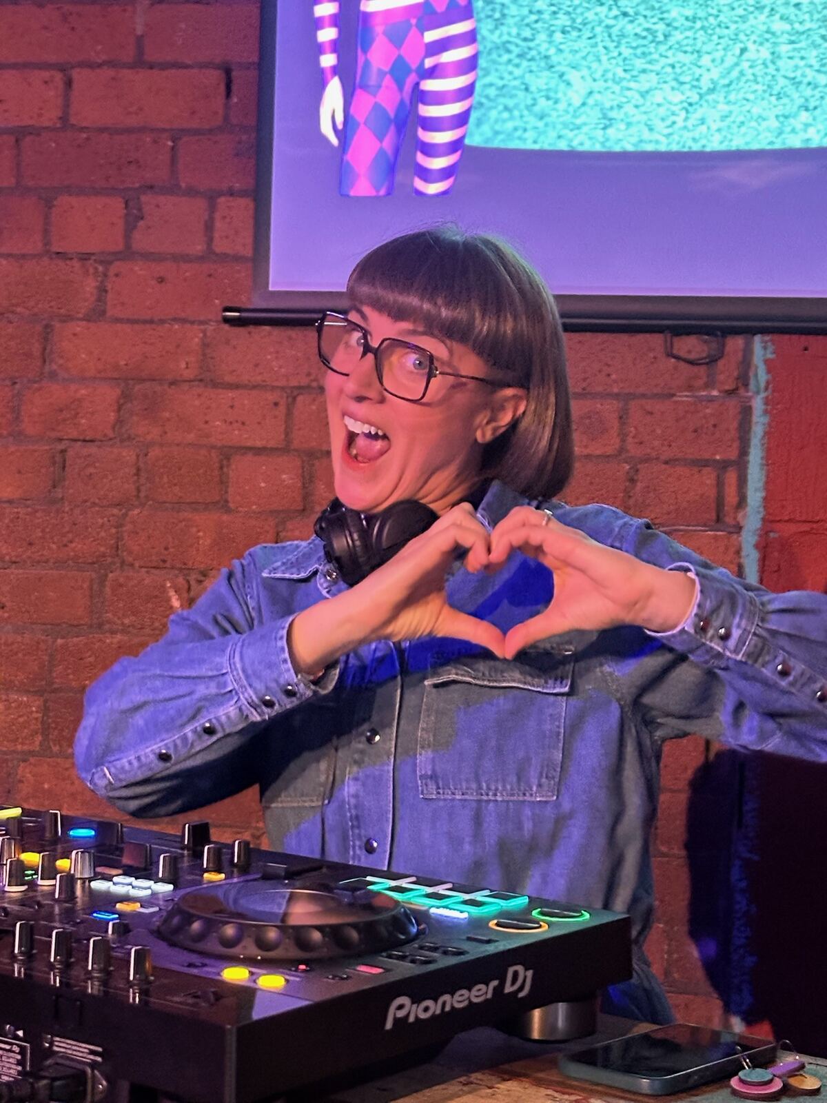 LooCee making a heart shape with her hands while DJing