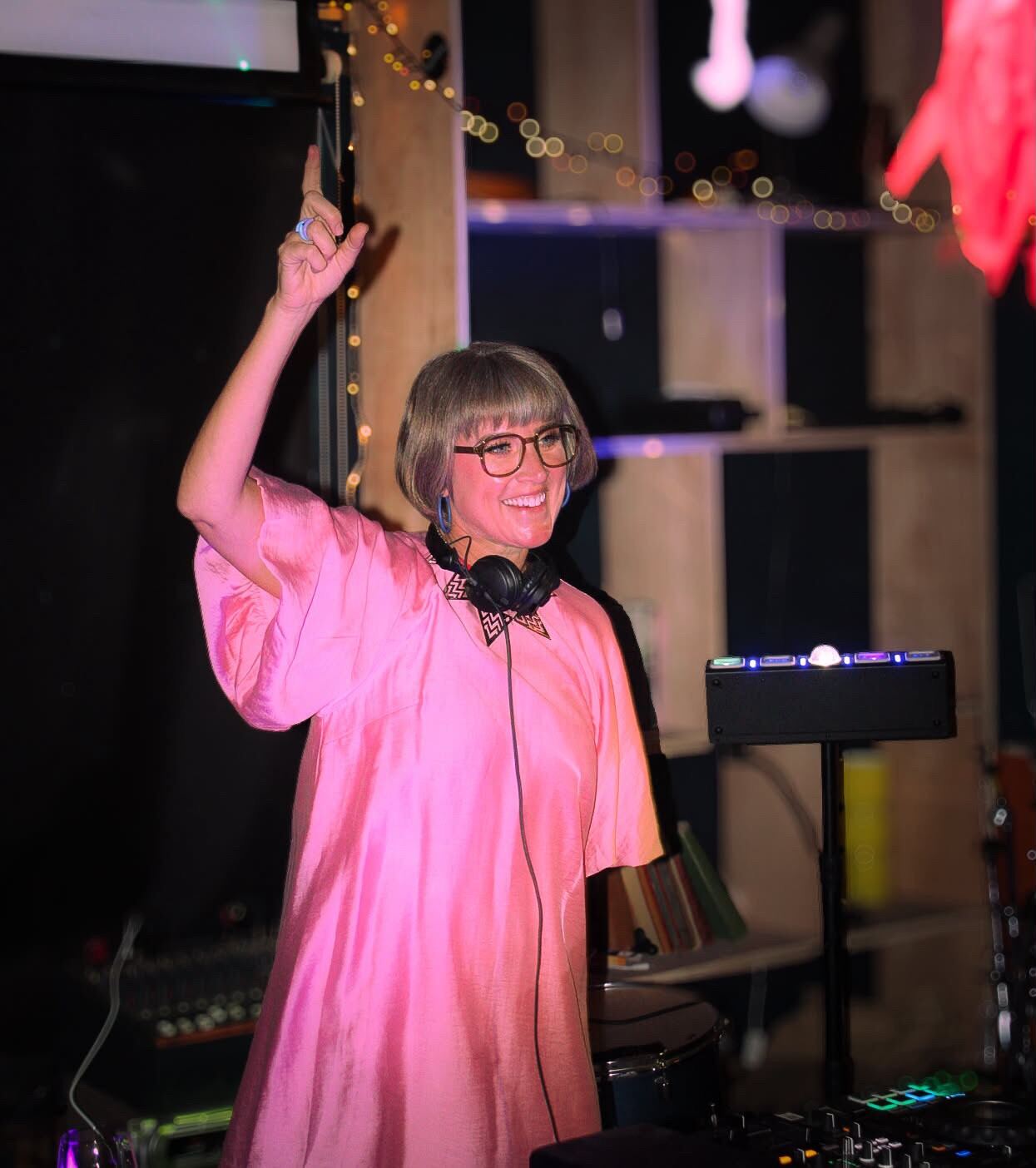 LooCee DJing at a private event, pointing to the crowd mid-set
